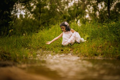 Free A young girl in white dress exploring the riverside in lush greenery during summer in Tumakuru, India. Stock Photo