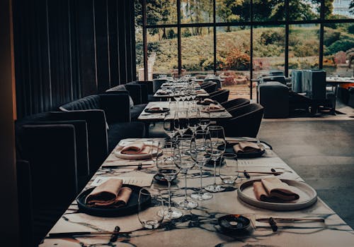 Elegant restaurant setup with well-arranged tables, glassware, and napkins, showcasing a scenic outdoor view.