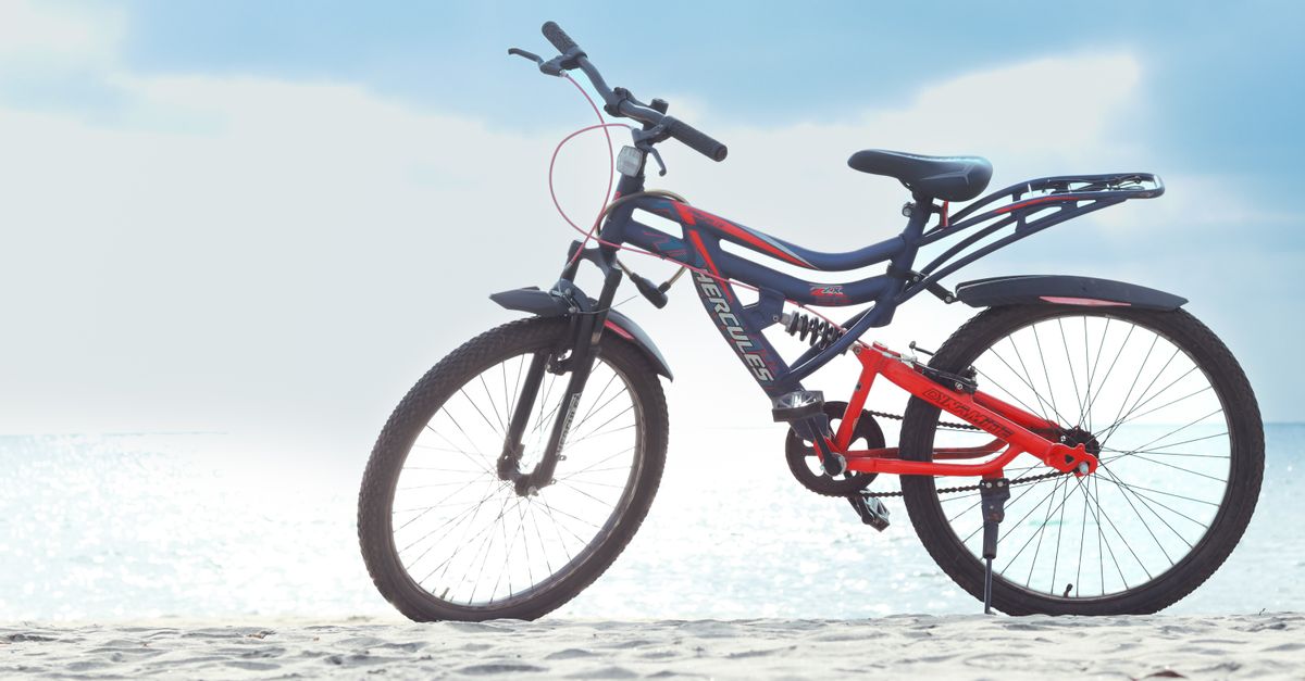 A vibrant bicycle stands on Alappuzha beach with a clear sky, ideal for adventure seekers.