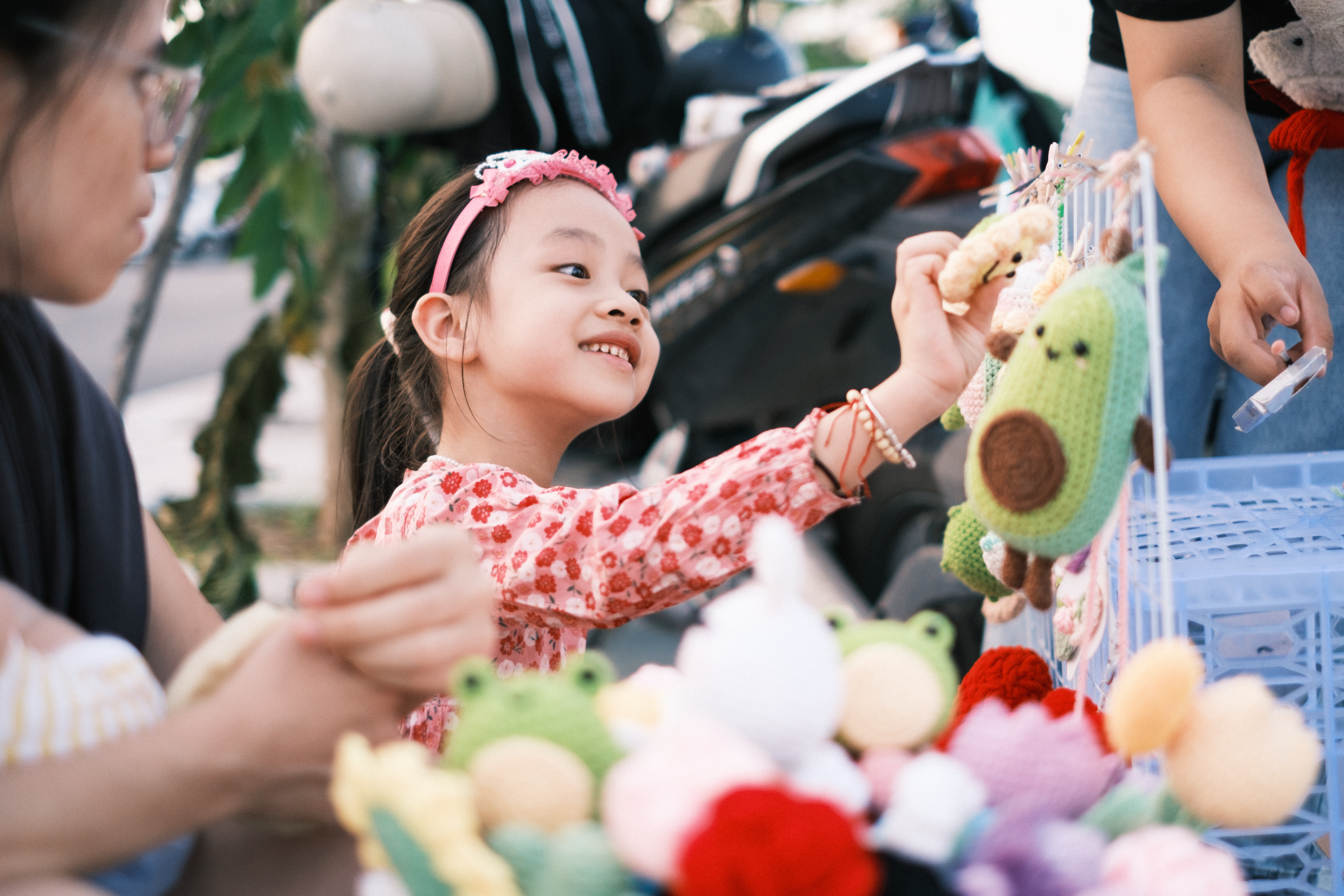 Joyful Child with Knitted Toys at Outdoor Market