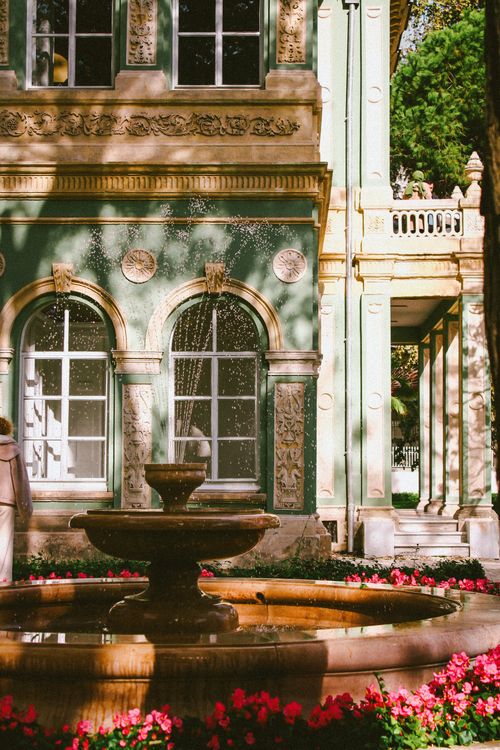 Free Beautiful stone fountain with floral decorations by a classic European architecture facade. Stock Photo