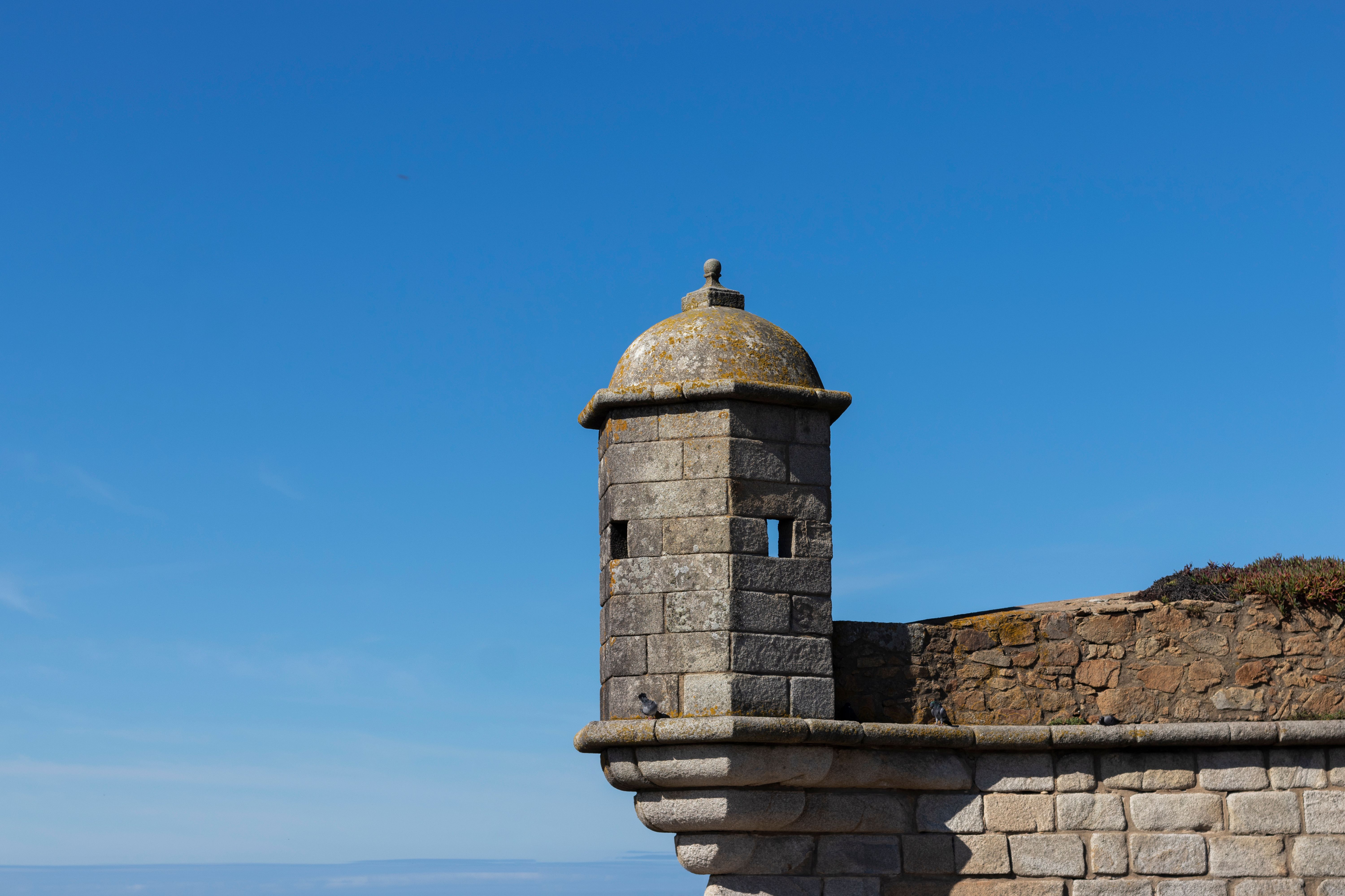 A historic stone tower set against a clear blue sky in Porto, Portugal. Stunning architecture.