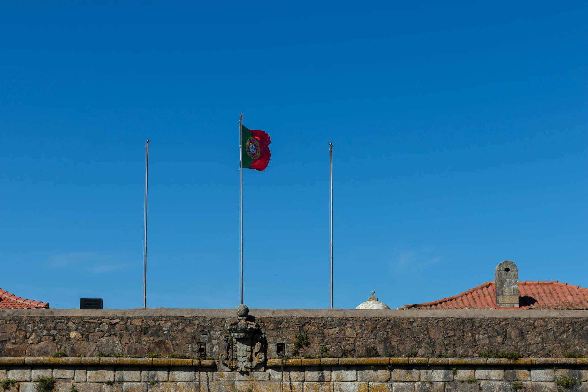 Portugisisk flagga på den historiska stenmuren i Porto