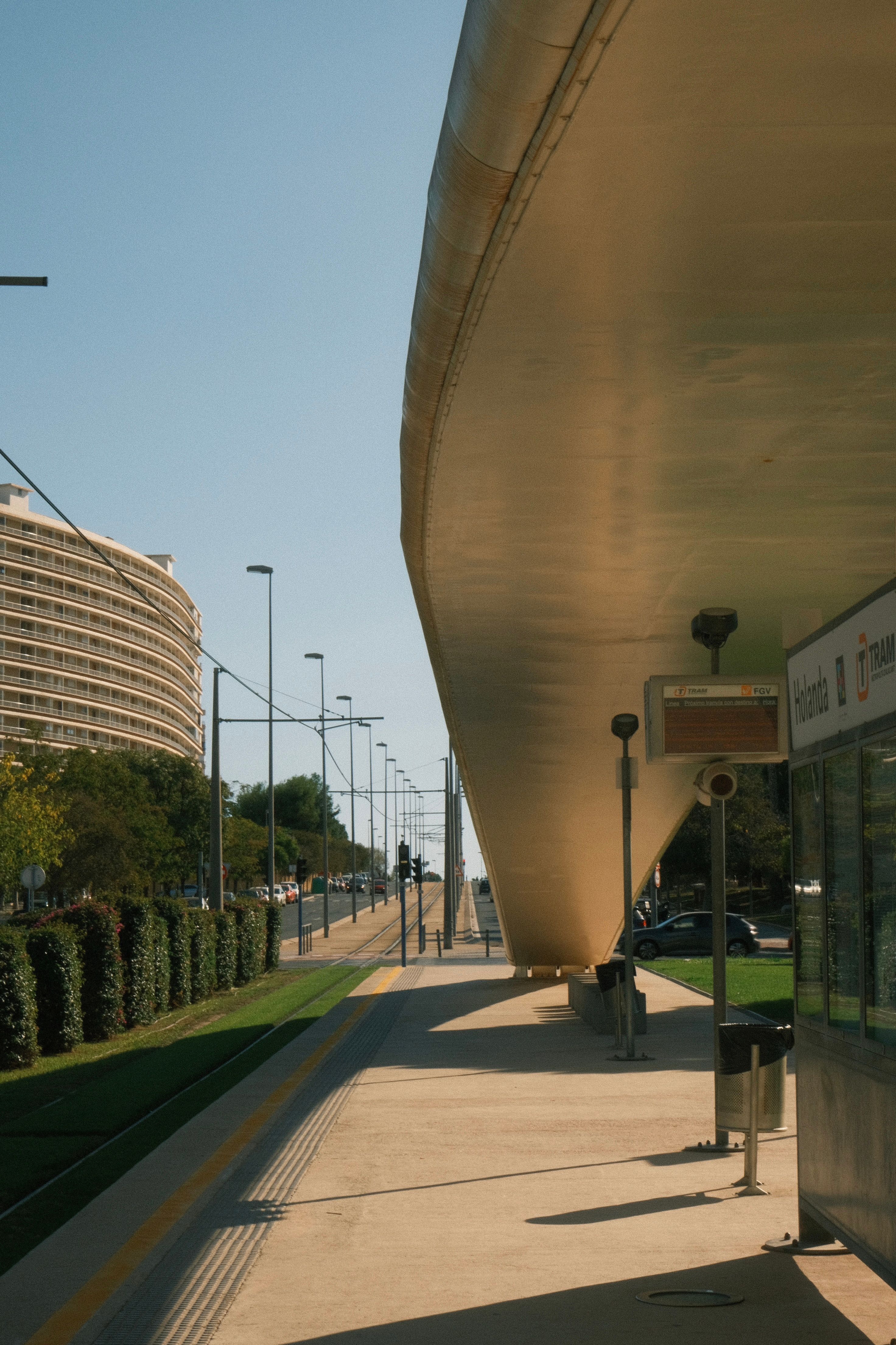 A modern tram station with sleek architecture in an urban setting, on a sunny day.