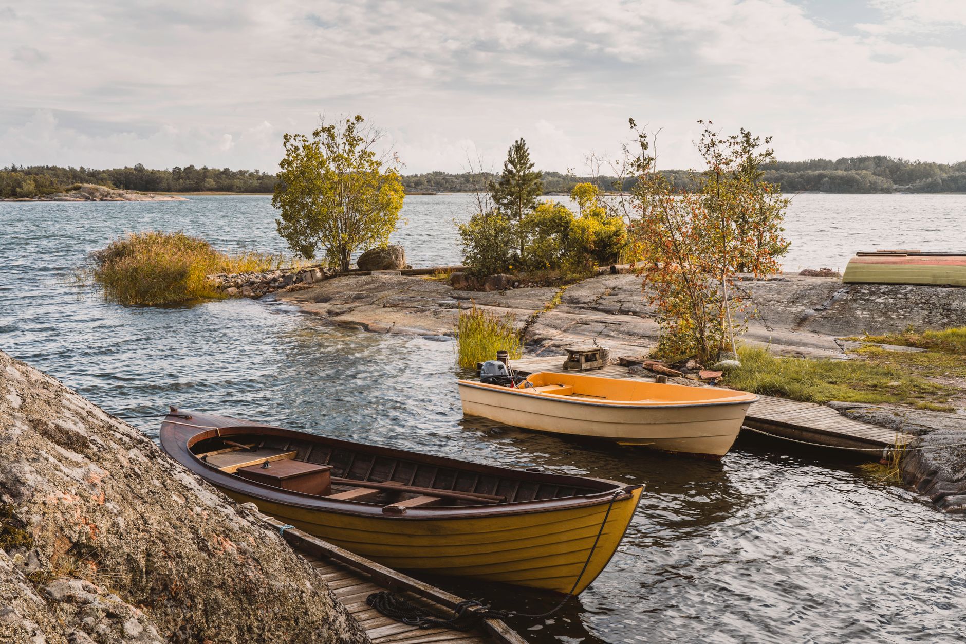 Beautiful wooden boats by the rocky shore in the serene Turku Archipelago.