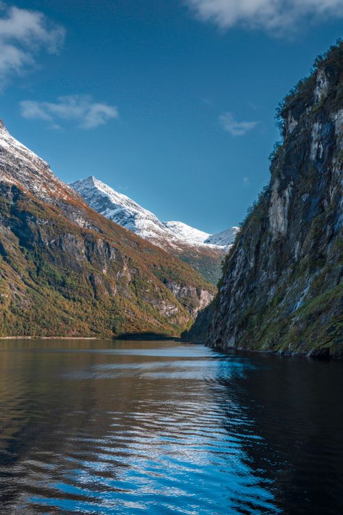 Free Stunning view of a Norwegian fjord surrounded by cliffs and reflective waters under a clear blue sky. Stock Photo