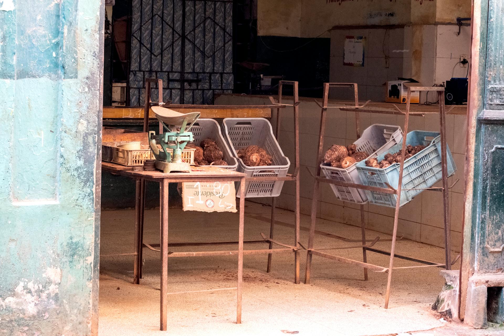 A rustic vegetable shop in Cuba with produce and weighing scale.