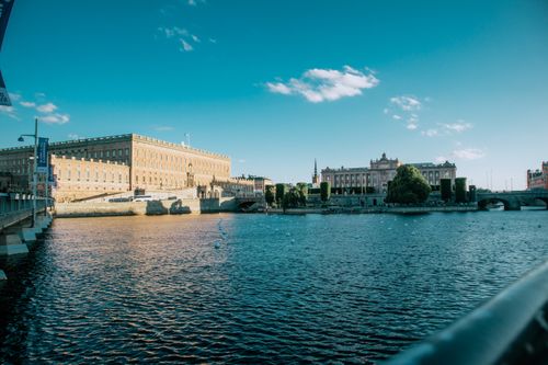 Free Beautiful daytime view of Stockholm's historic Royal Palace with clear blue sky and waterfront. Stock Photo