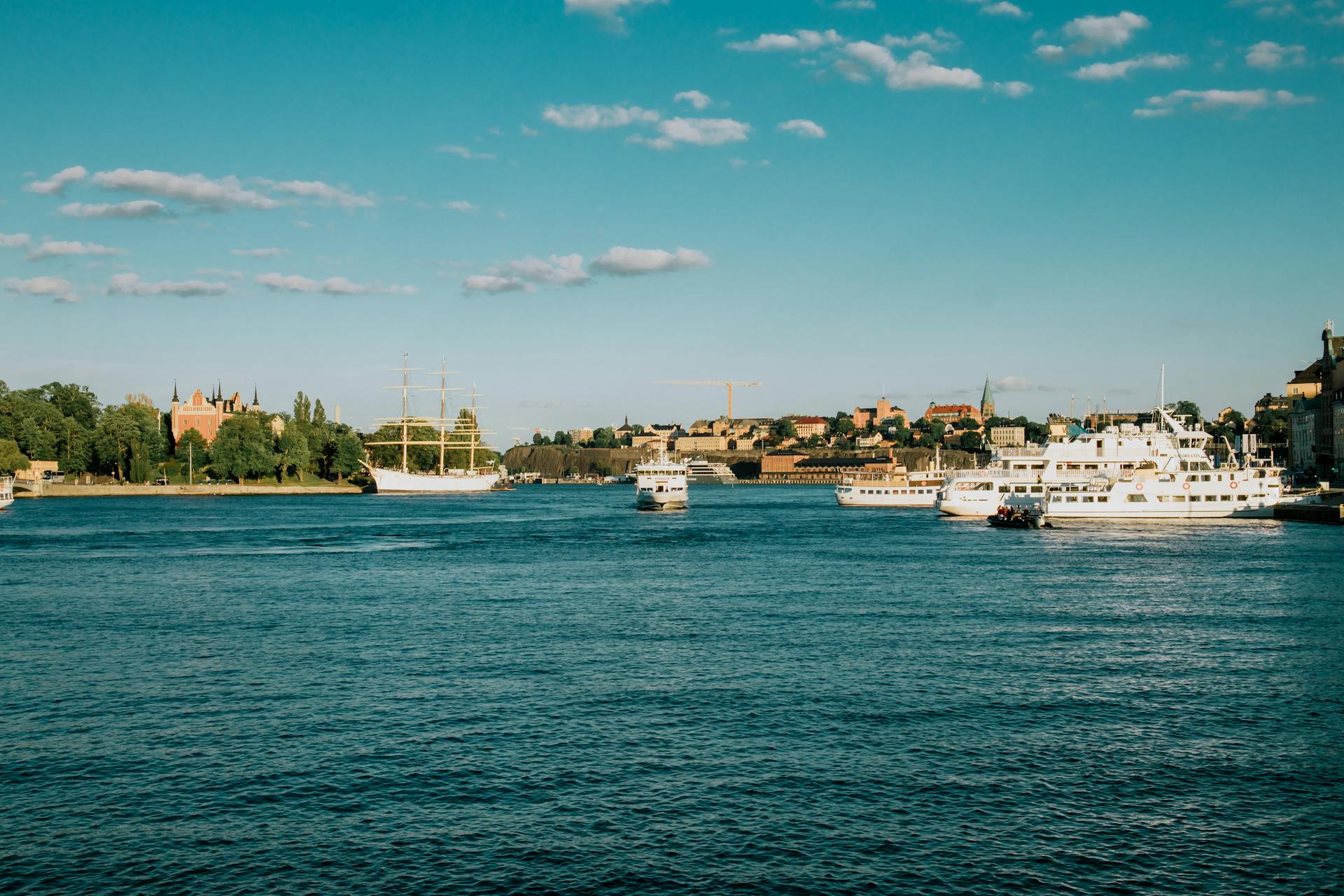 Sunny summer day on the Stockholm waterfront with cruise ships and iconic city skyline in view.