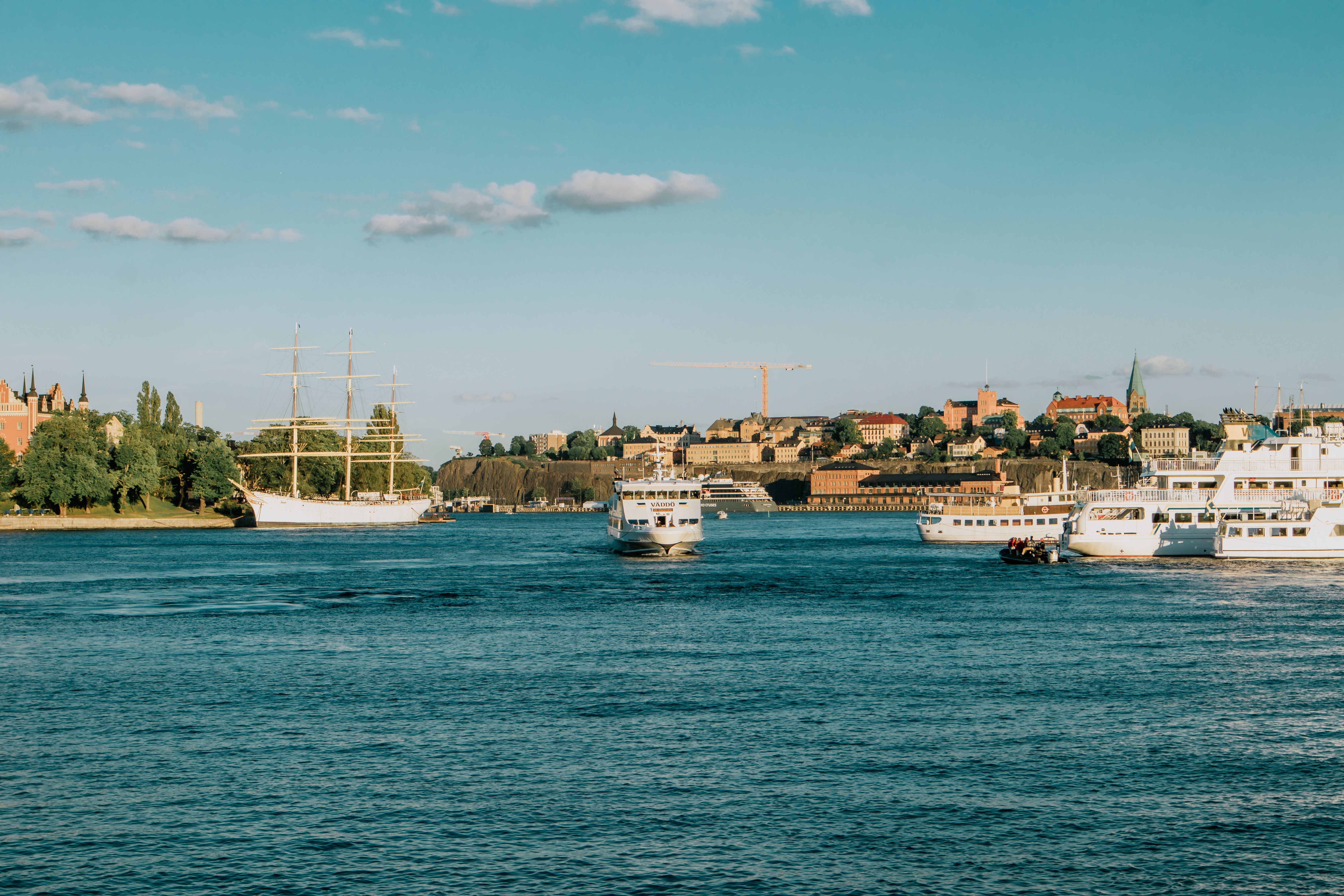 Stockholm waterfront with boats against a vibrant city skyline under a clear blue sky.