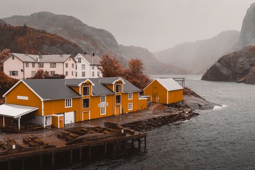 Free Charming yellow buildings by the fjord in Nusfjord, Lofoten, capturing a misty autumn ambiance. Stock Photo