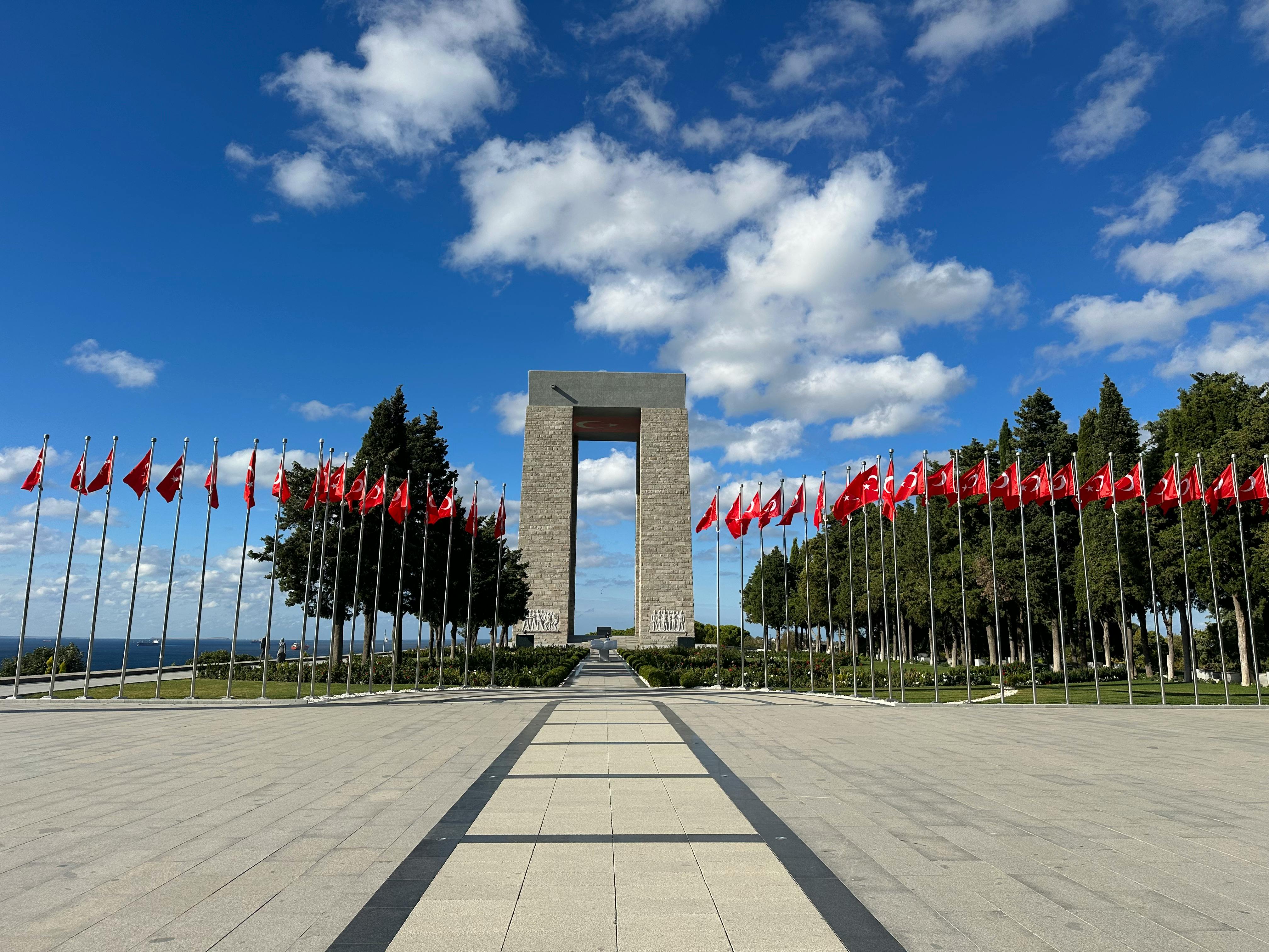 Gallipoli Monument with rows of Turkish flags under a bright blue sky.