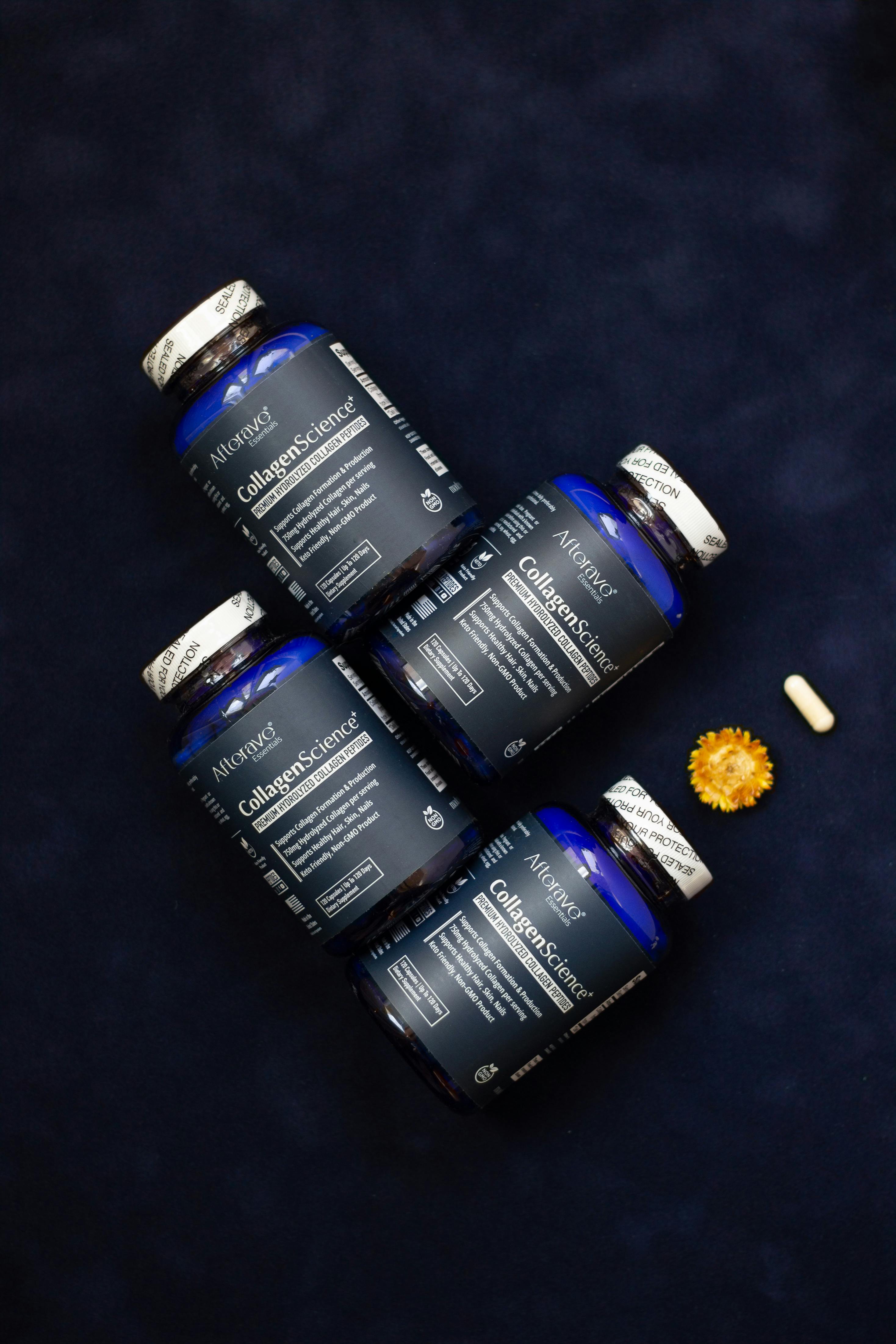 Blue bottles of collagen supplements arranged with a flower and a capsule.