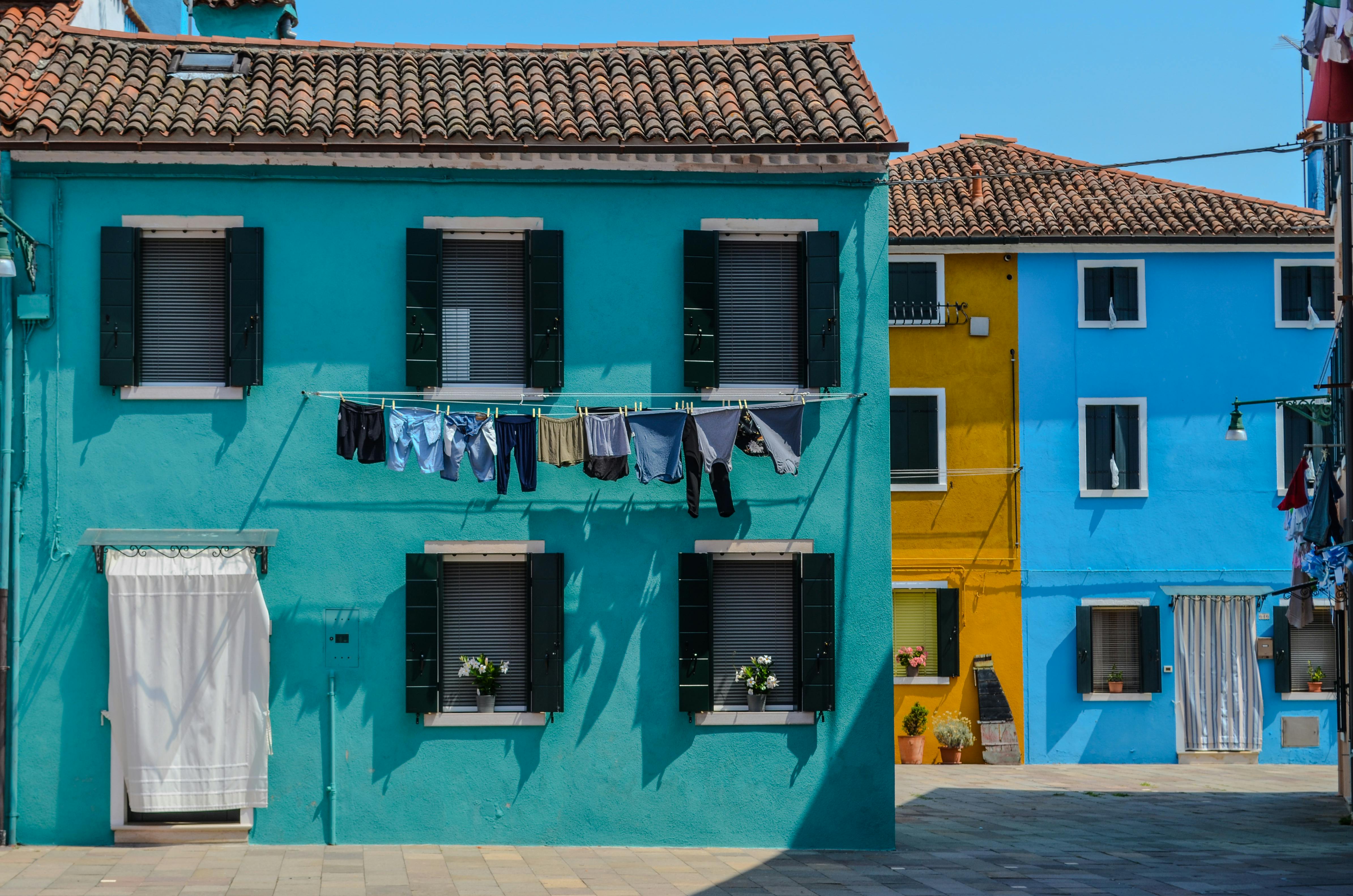 Brightly colored houses in Venice with laundry drying in the sun, showcasing Italian charm.