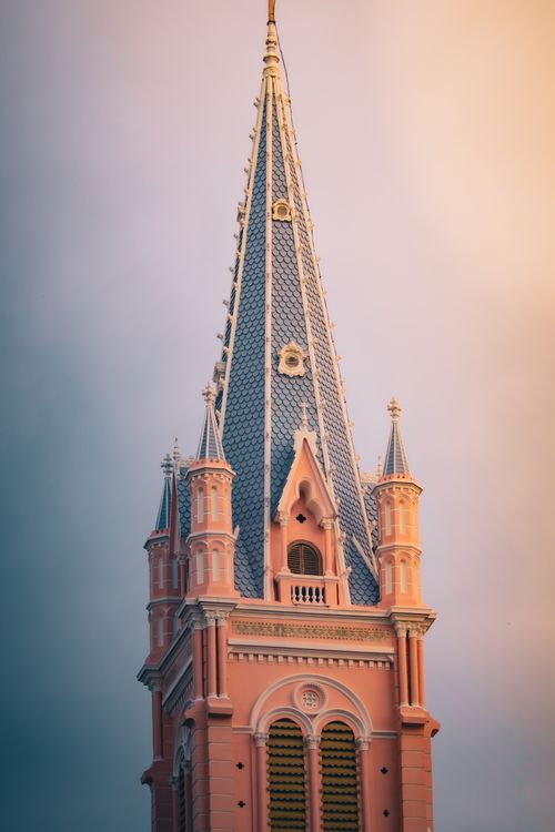 Free Detailed view of a pink neo-gothic church spire against a serene evening sky. Stock Photo