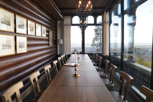 Luxurious dining room with long table, wooden decor, and panoramic view.