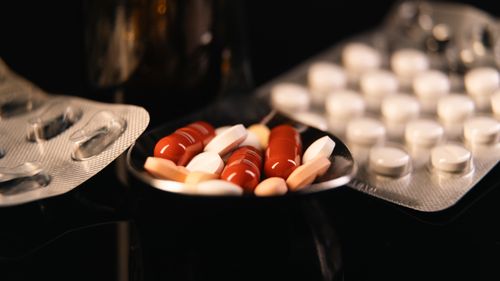 Free Close-up of assorted pharmaceutical pills in blister packs and a spoon on a dark background. Stock Photo
