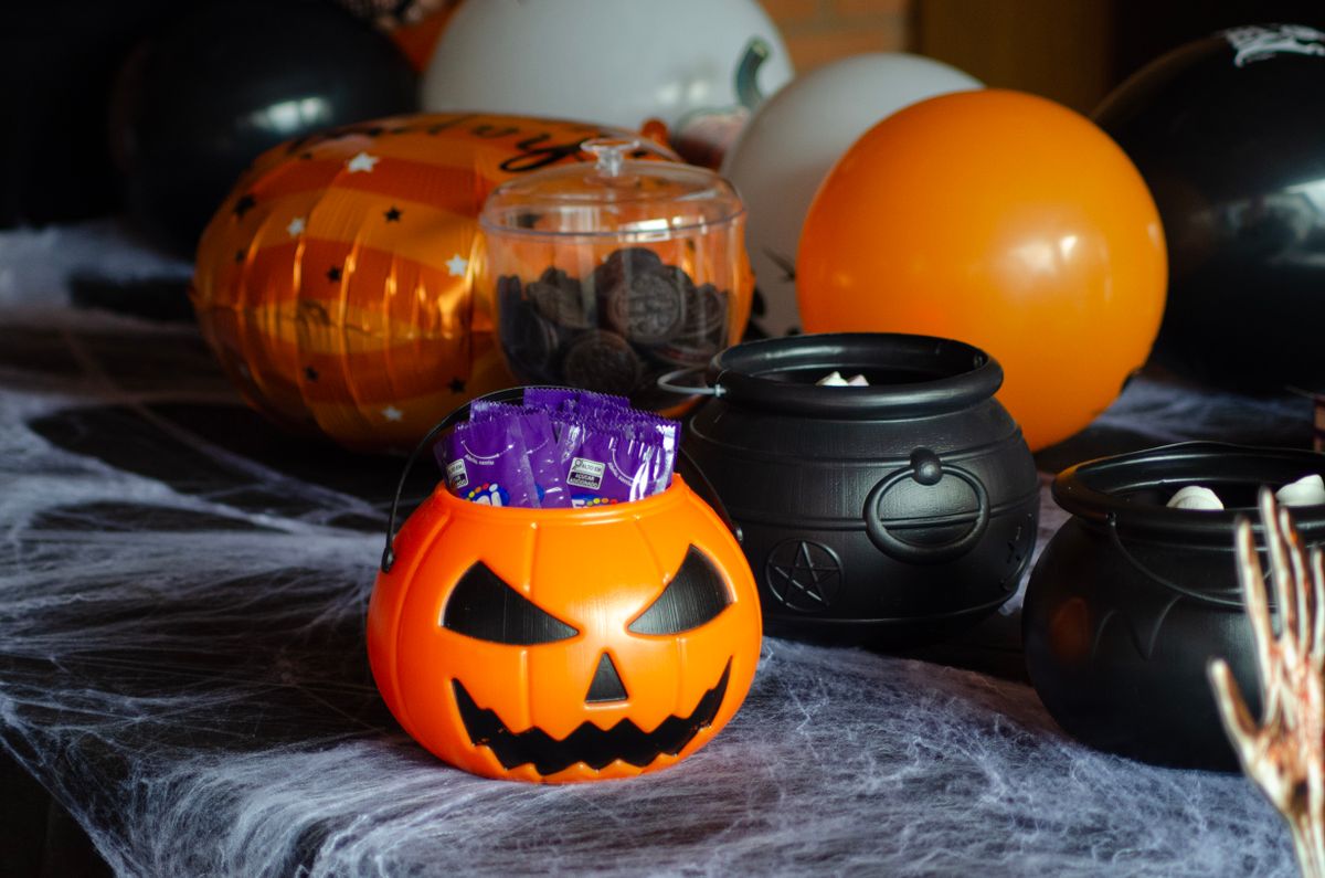 Halloween candy display with a pumpkin bucket and mini cauldrons on a table