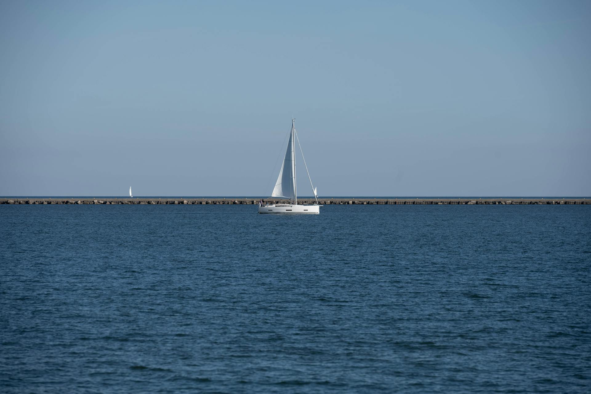 A tranquil scene of a sailboat gliding on Lake Michigan near Milwaukee's shore.