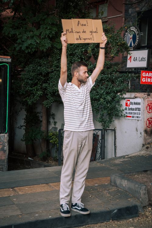 Free Man holding sign in bustling urban environment, standing on street. Stock Photo