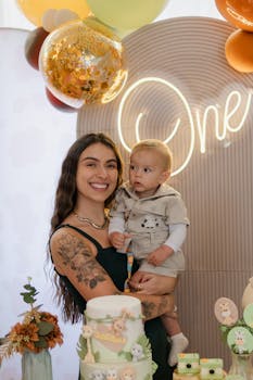A joyful mother with her baby celebrating his first birthday with a cake and decorations.