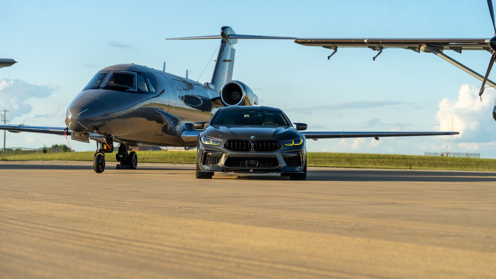 A luxury car parked beside a private jet on a runway