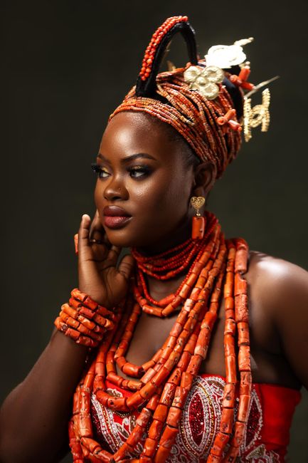 Beautiful portrait of a Nigerian woman in elaborate traditional attire with vibrant coral beads, showcasing cultural elegance.
