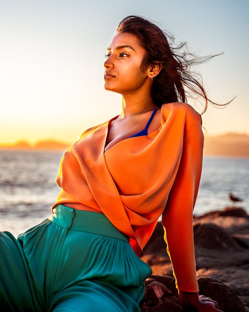 Photo of Woman Sitting on the Beach Posing During Golden Hour