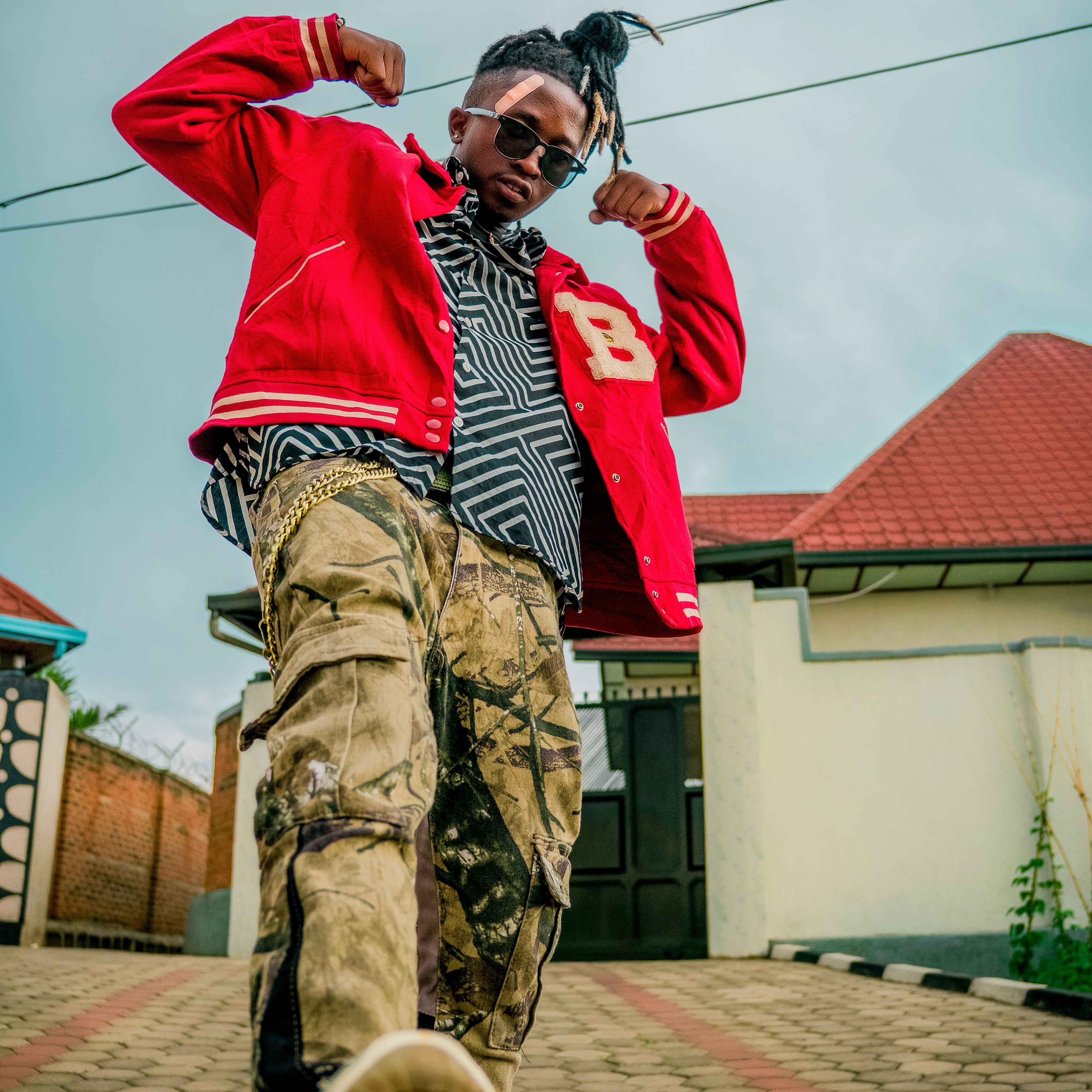 Trendy individual posing with a red jacket and casual attire in an urban outdoor setting.