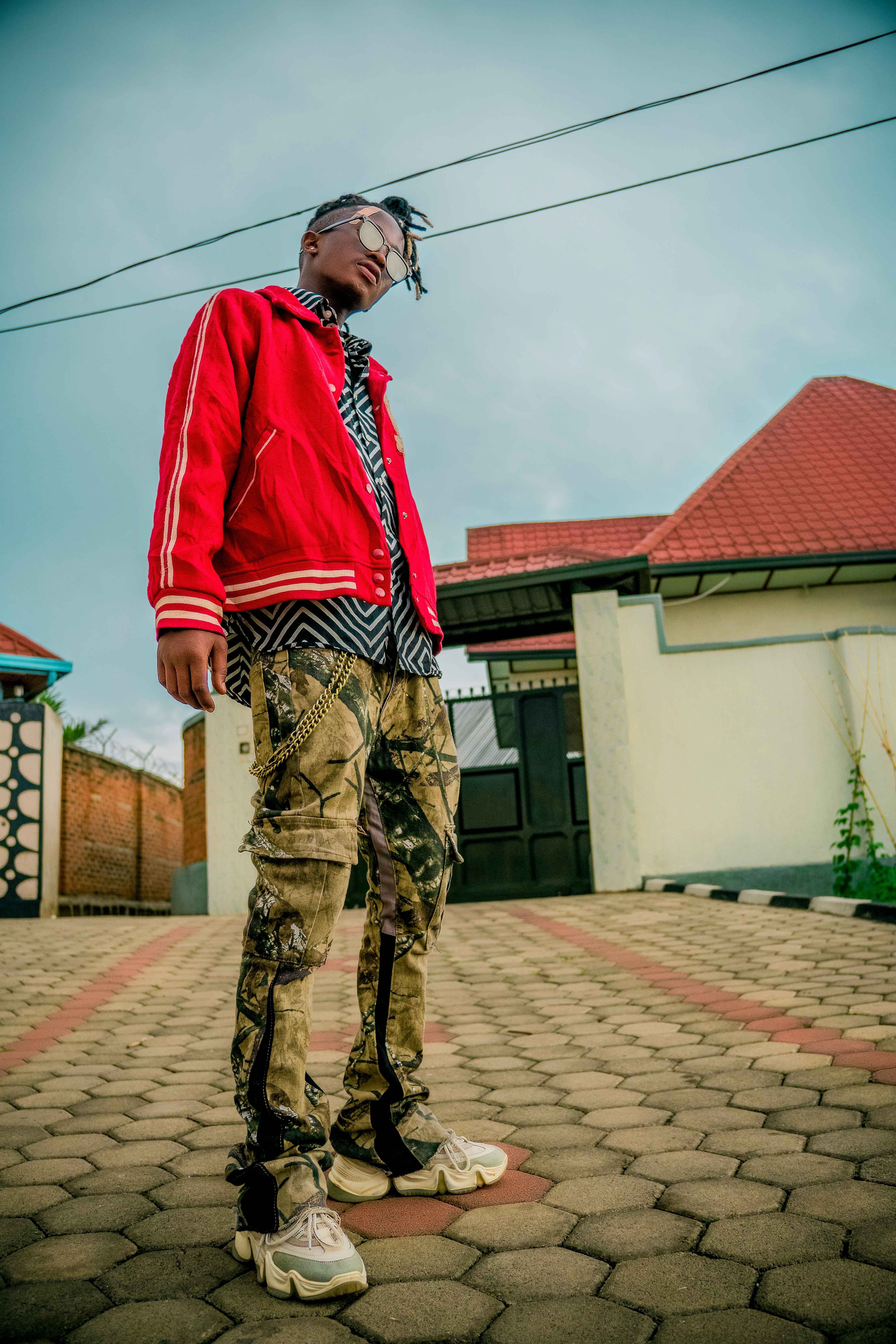 Stylish young adult poses confidently in vibrant streetwear outdoors.