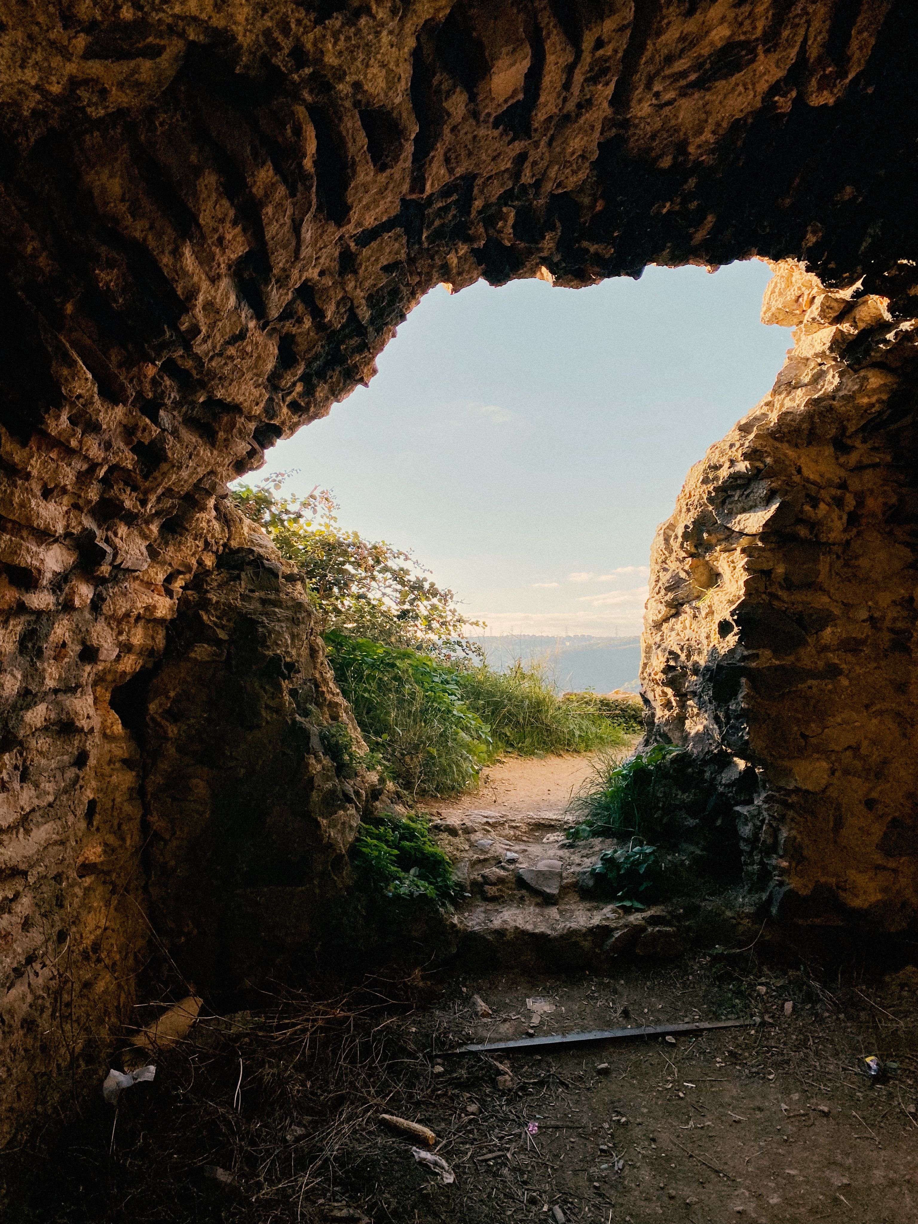 View from Inside a Rocky Cave to a Scenic Pathway · Free Stock Photo