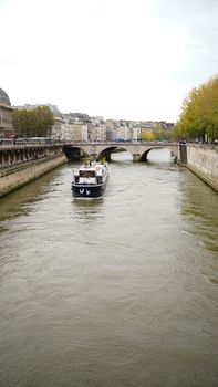 A boat navigates the Seine River under a historic bridge in Paris, France.