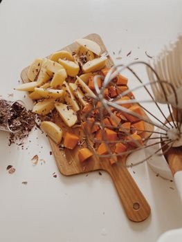 Freshly chopped potatoes and squash on a wooden board with spices, perfect for cooking inspiration.