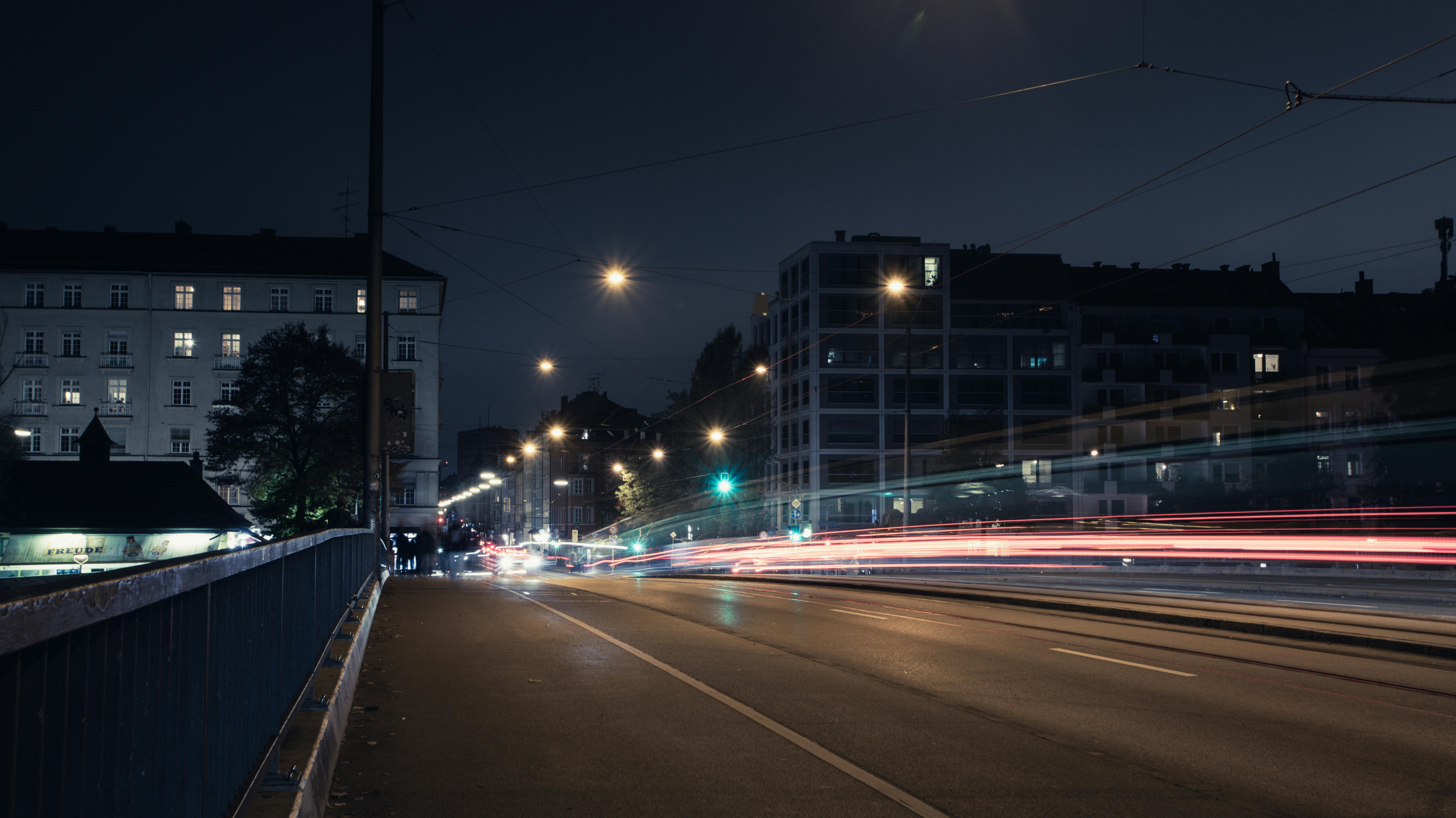 Urban night scene in Munich, Germany, showcasing street lights and vehicle light trails on a quiet road.