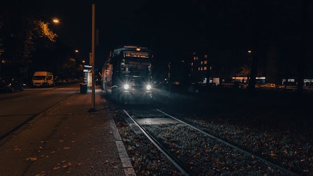 A tram approaches a stop at night in Munich, showcasing urban nightlife and transport.