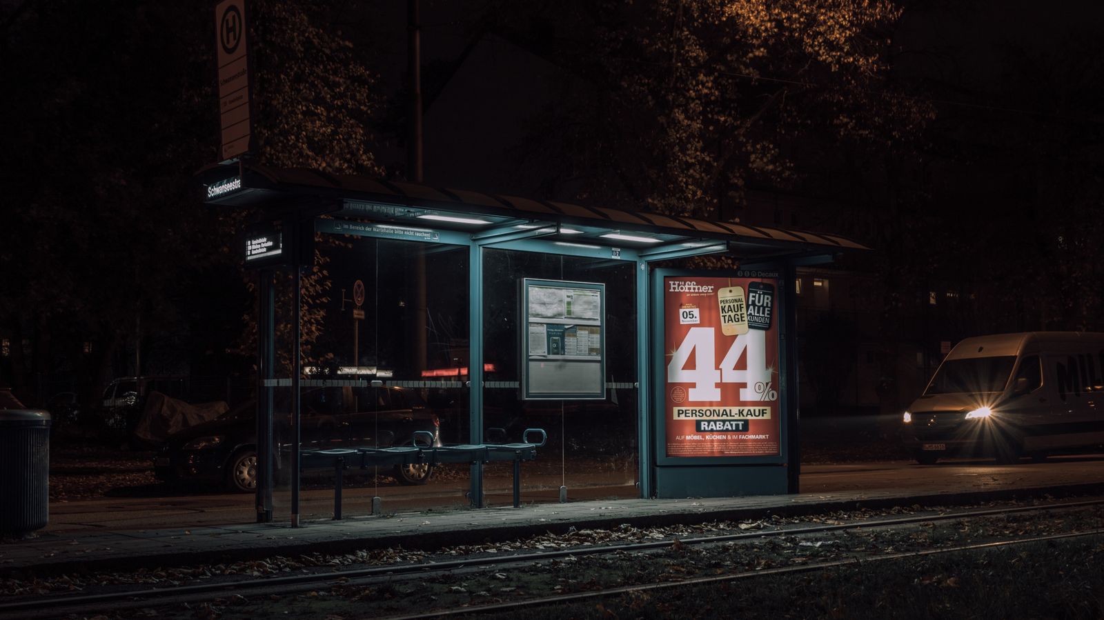 Bus shelter at night with an illuminated poster panel
