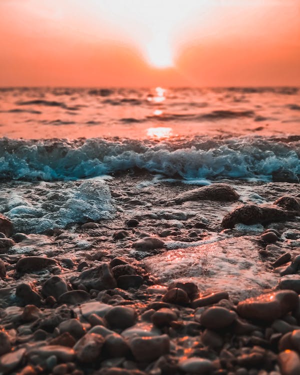 Photo of Stones and Waves During Golden Hour