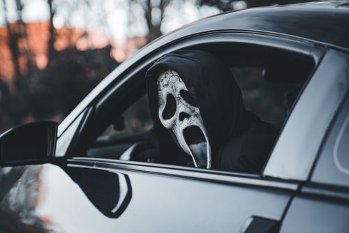 Free Eerie photo of a person in a ghost mask inside a car, perfect for Halloween themes. Stock Photo