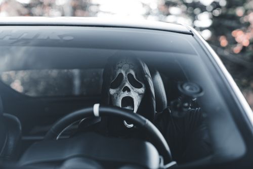 Free Masked individual in car adds an eerie vibe, suitable for Halloween themes. Stock Photo