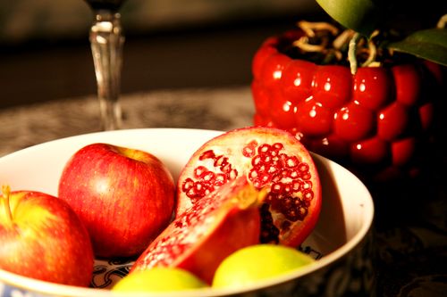 Free Colorful fruit bowl featuring apples and a sliced pomegranate, with a red pot and plant decor. Stock Photo