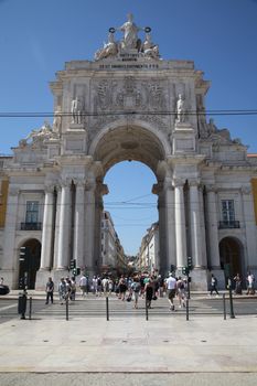 Explore the iconic Rua Augusta Arch in Lisbon, Portugal, bustling with people under a clear blue sky.