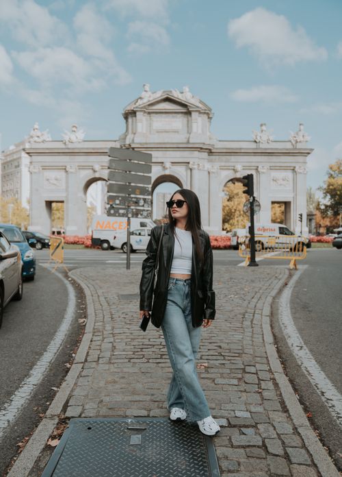 Free Woman in trendy outfit standing near Puerta de Alcalá in Madrid, Spain, under a clear sky. Stock Photo