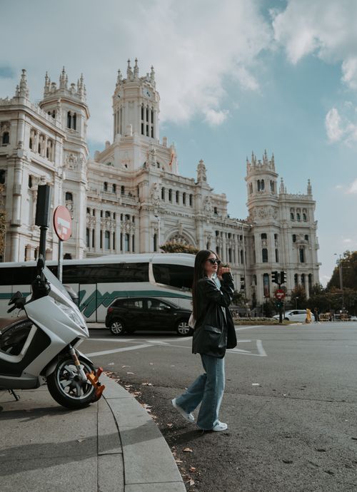 Free Woman photographing City Hall in Madrid's bustling street scene. Stock Photo