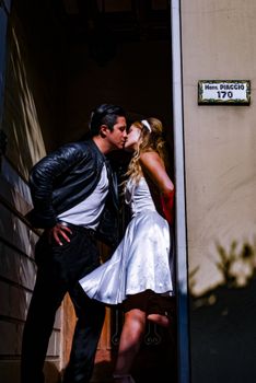 Couple in vintage attire shares a passionate kiss on the street corner.