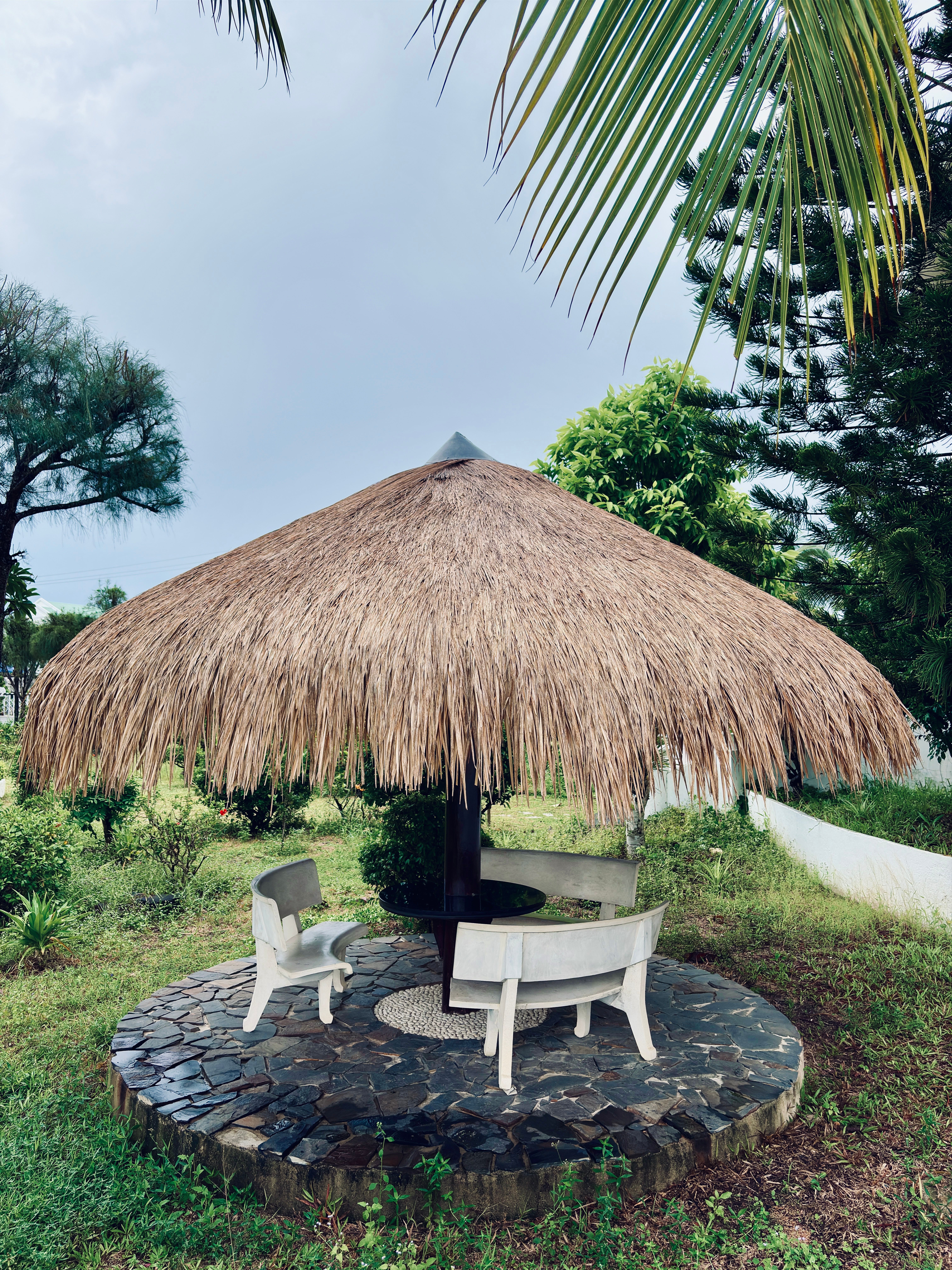 Rustic thatched gazebo in lush garden, Guinea
