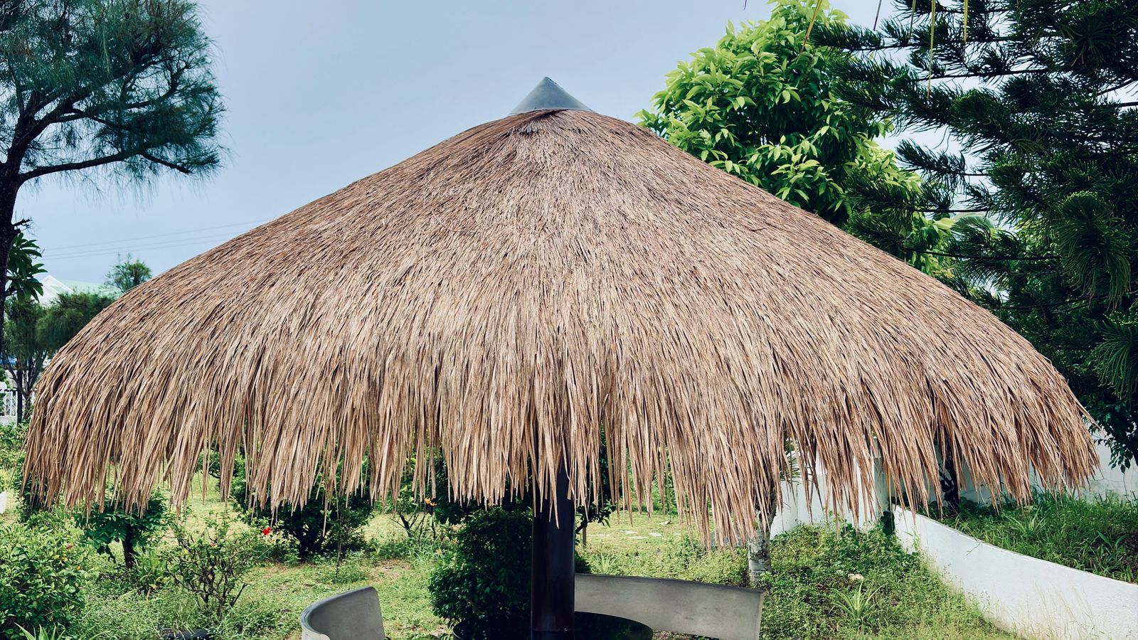 Rustic thatched gazebo in lush garden, Guinea