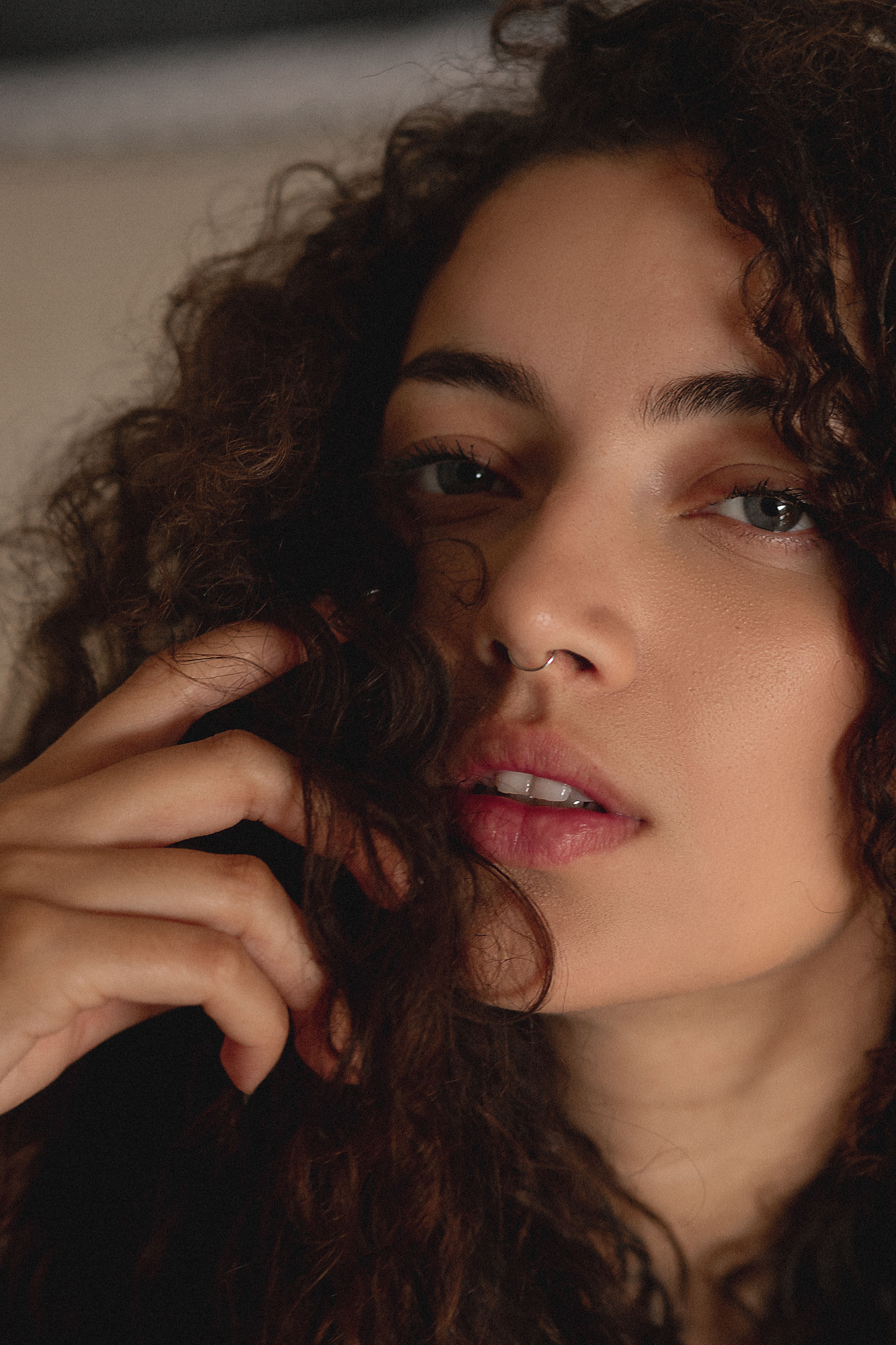 A detailed close-up portrait of a woman with curly hair and natural makeup.