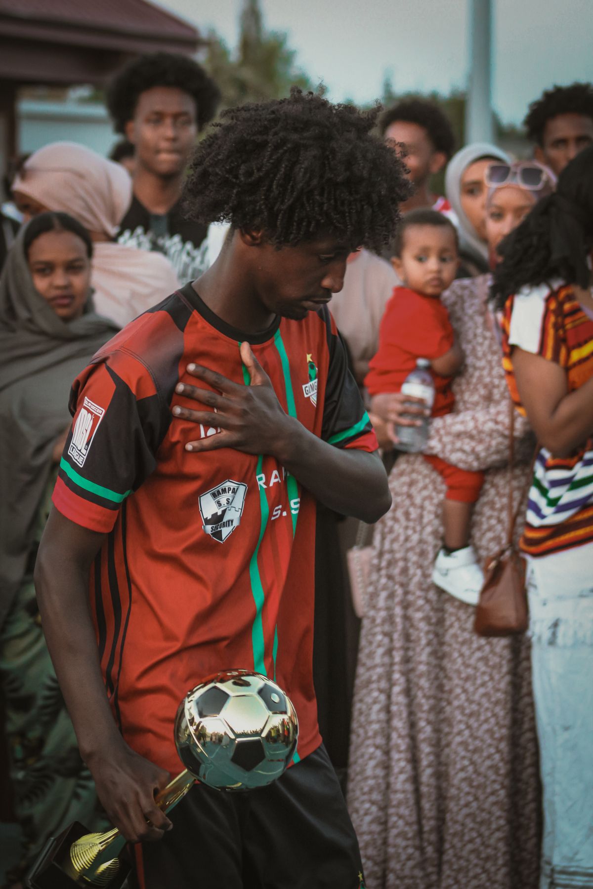A soccer player holding a trophy surrounded by a cheering crowd