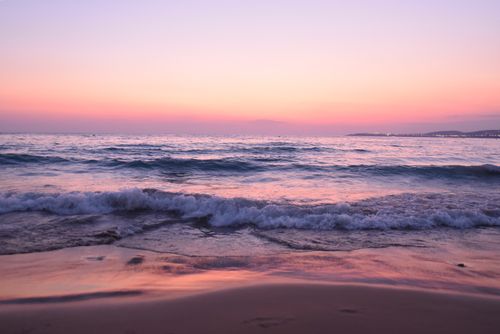 Free Beautiful sunset over the ocean with gentle waves and a pastel sky. Stock Photo