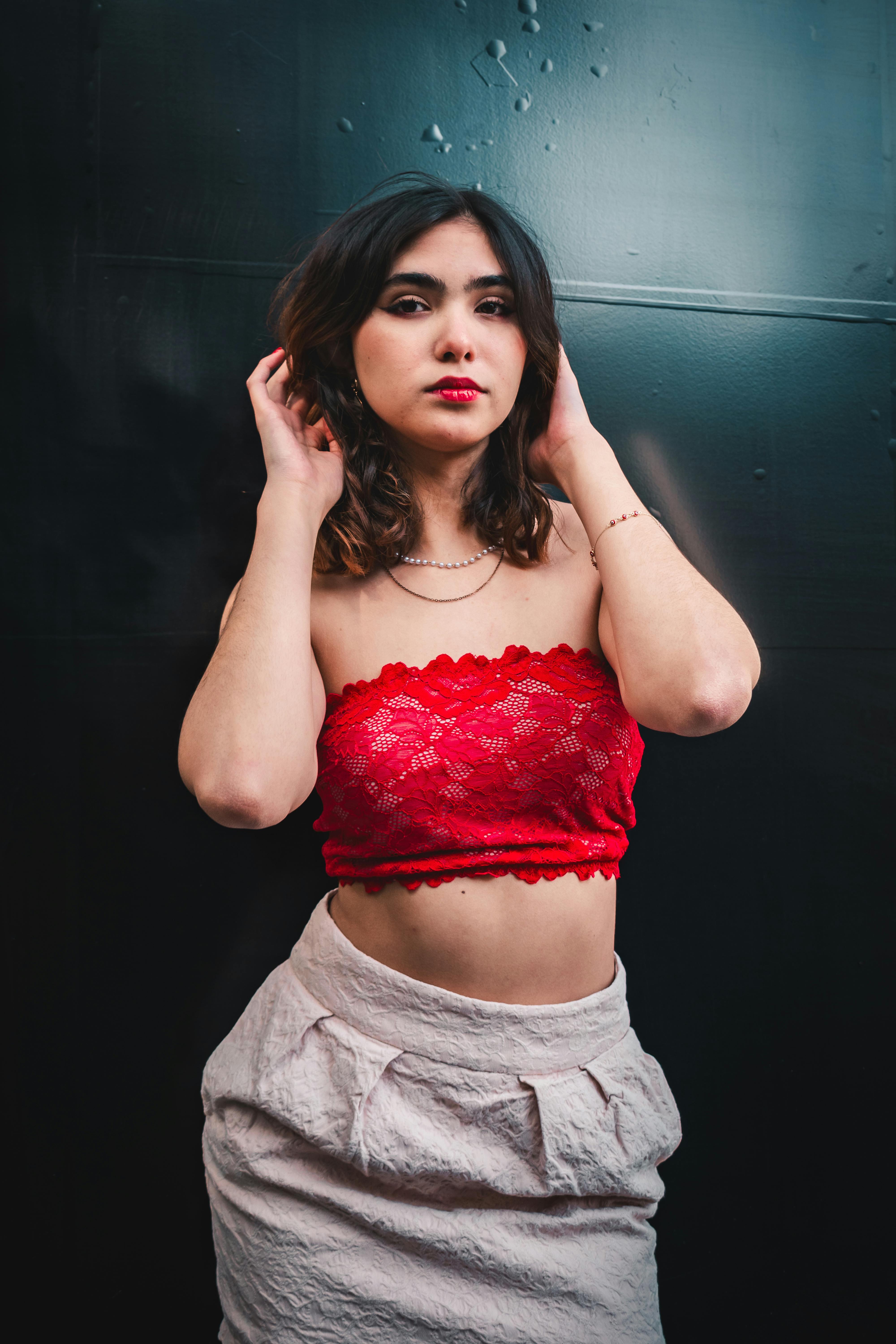 Gratis Donna Elegante In Top Rosso In Posa Su Sfondo Scuro Foto a disposizione